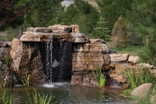 Natural rock waterfall spillway enhancing a resort-style pool atmosphere